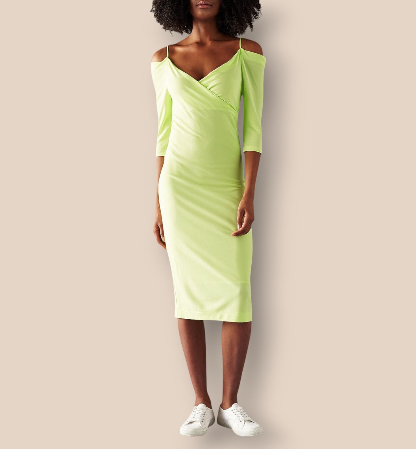 Person wearing a light green dress with white sneakers on a beige background