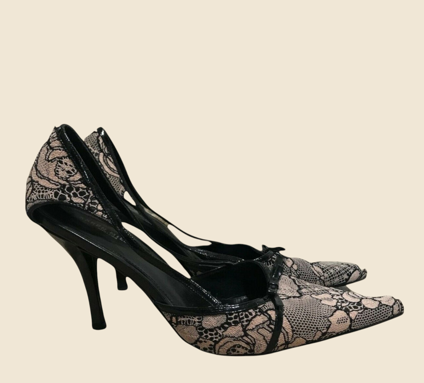 Black high-heeled shoes with snake print on a beige background