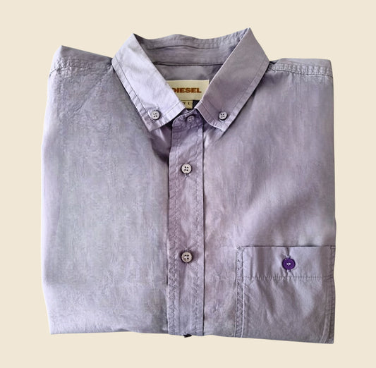 Folded lilac shirt with a visible brand label on a beige background
