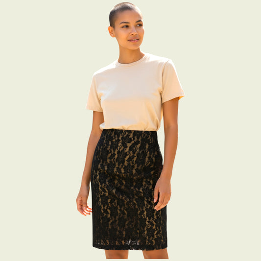 Woman wearing a beige top and black lace skirt on a light green background