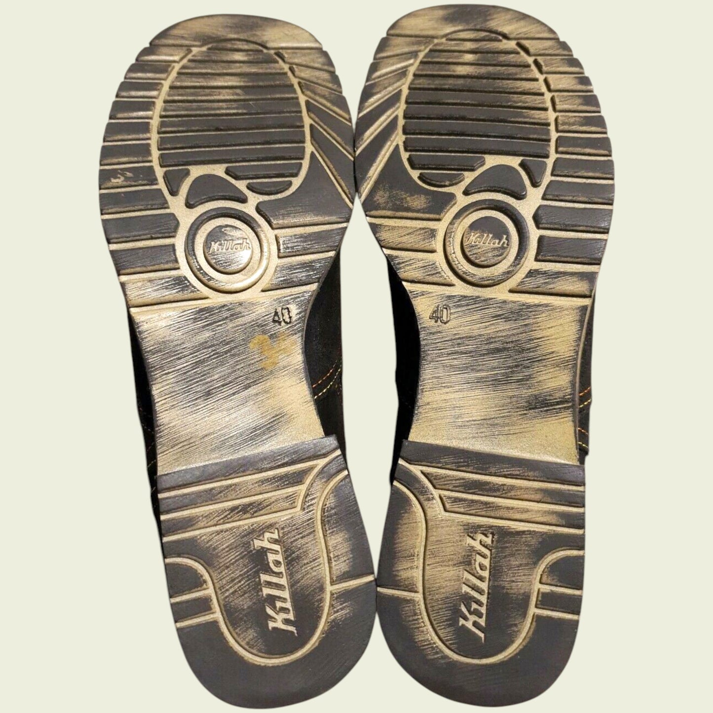 View of boot soles showing wear on beige background