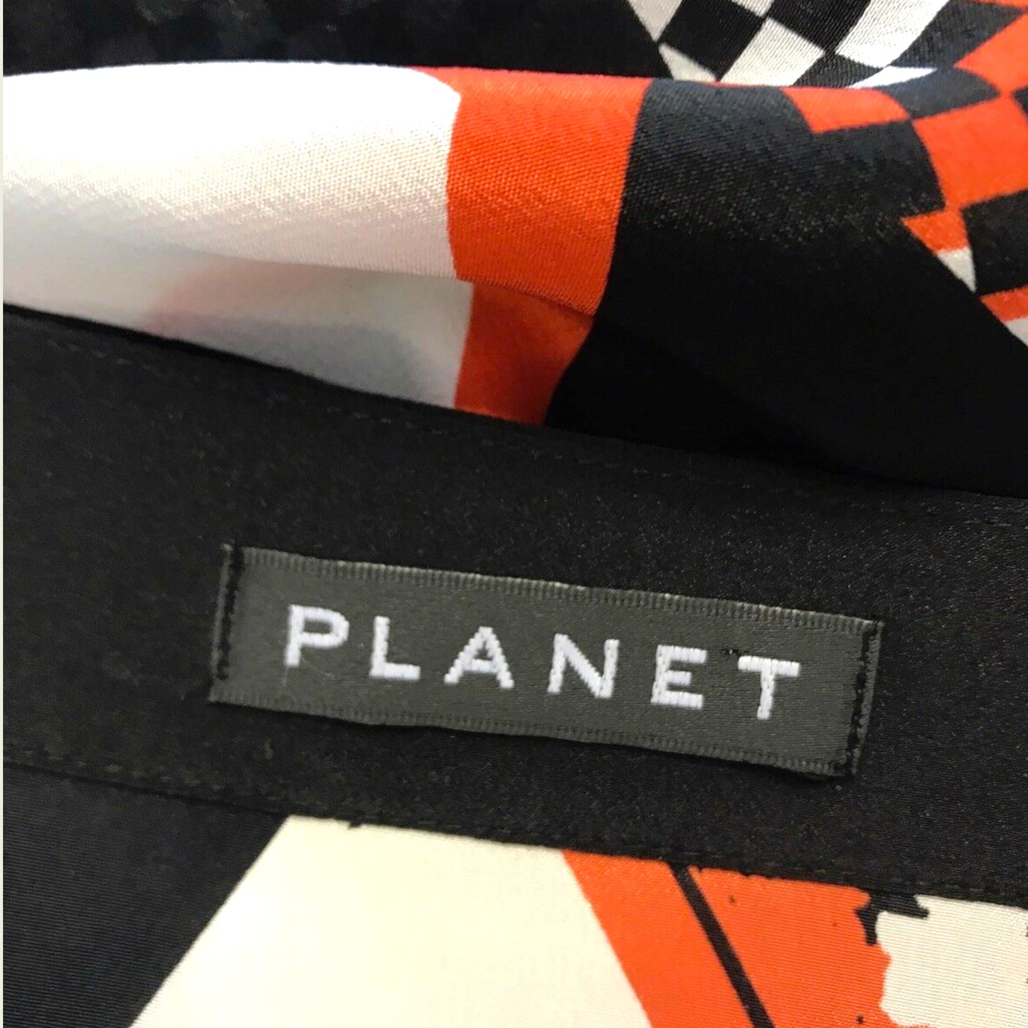 Close-up of a black fabric with a colorful pattern and 'PLANET' label.