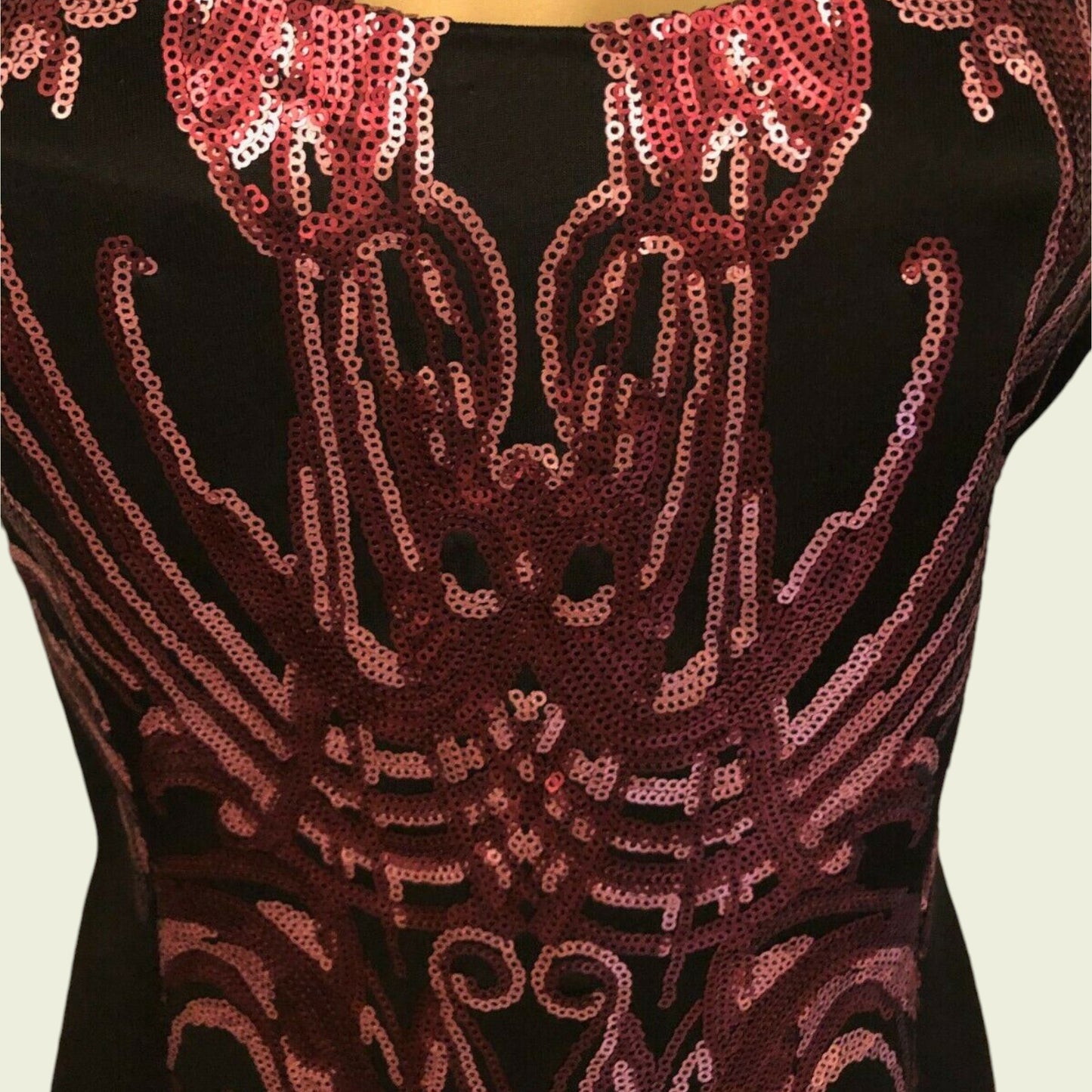 Black top with red sequin pattern on a beige background