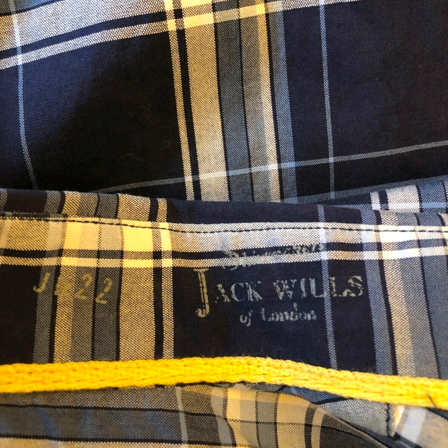 Close-up of a plaid fabric with 'Jack Wills' branding and a yellow waistband.
