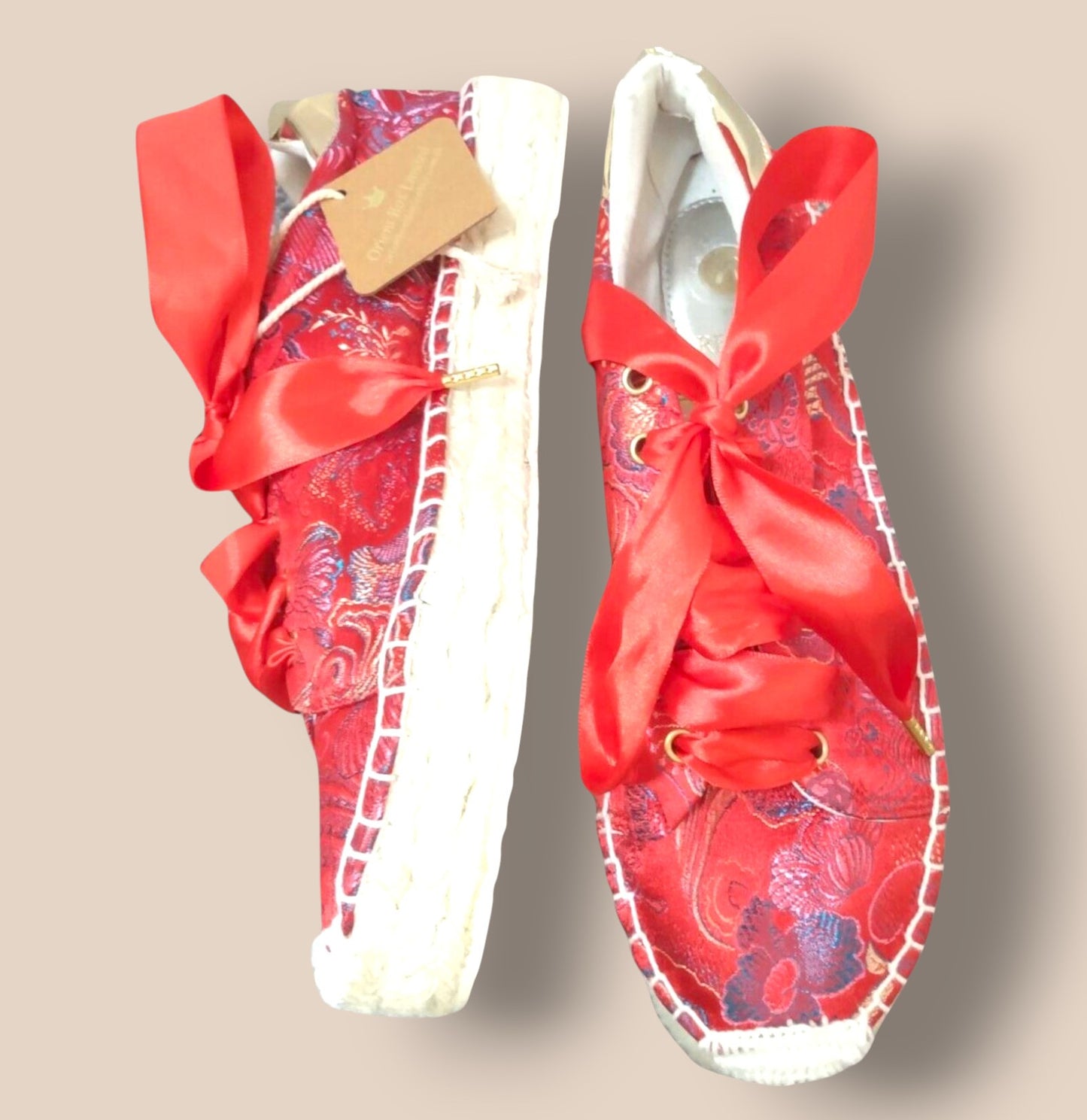 Red floral-patterned shoes with a large bow on a beige background