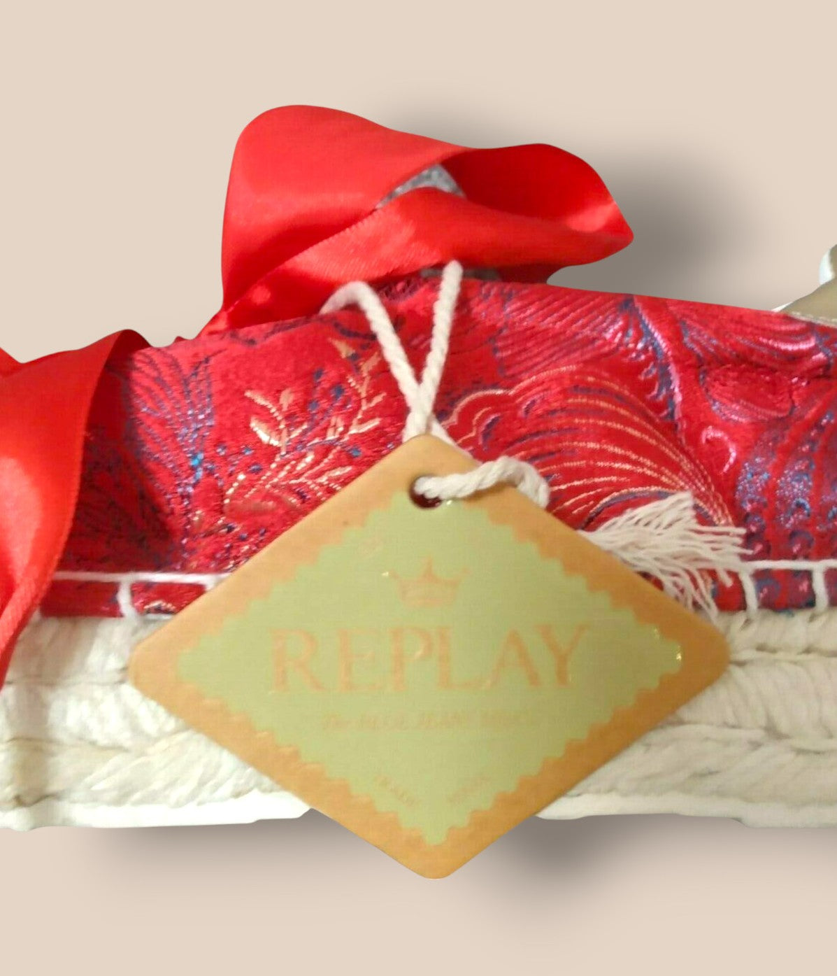 Product with a red bow and 'Replay' tag on a beige background
