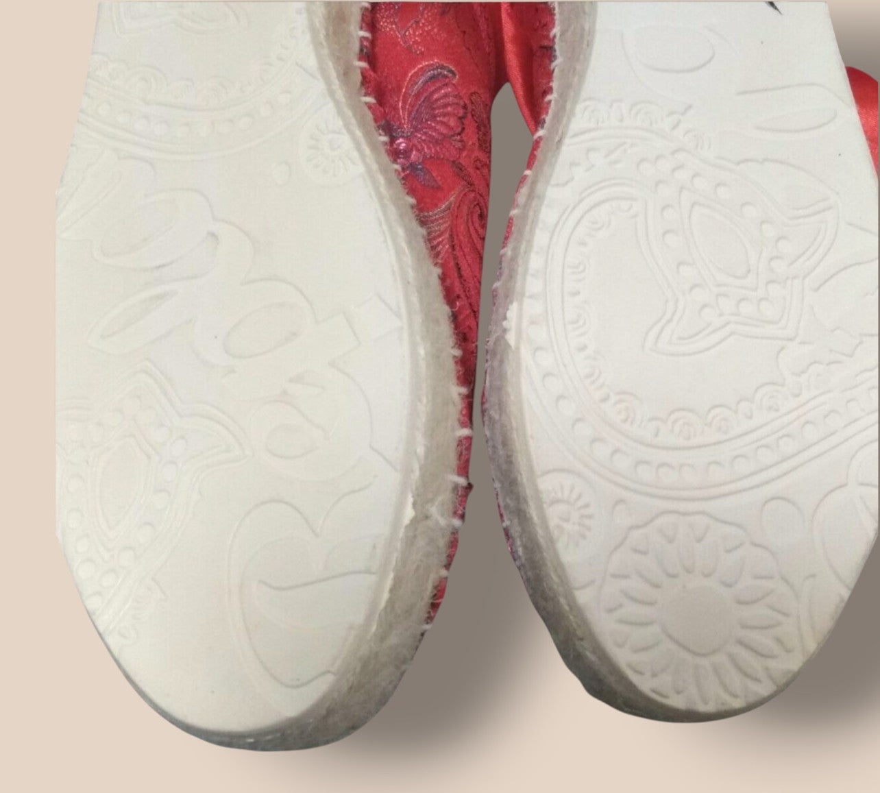 Close-up of a red and white shoe sole with intricate patterns on a beige background