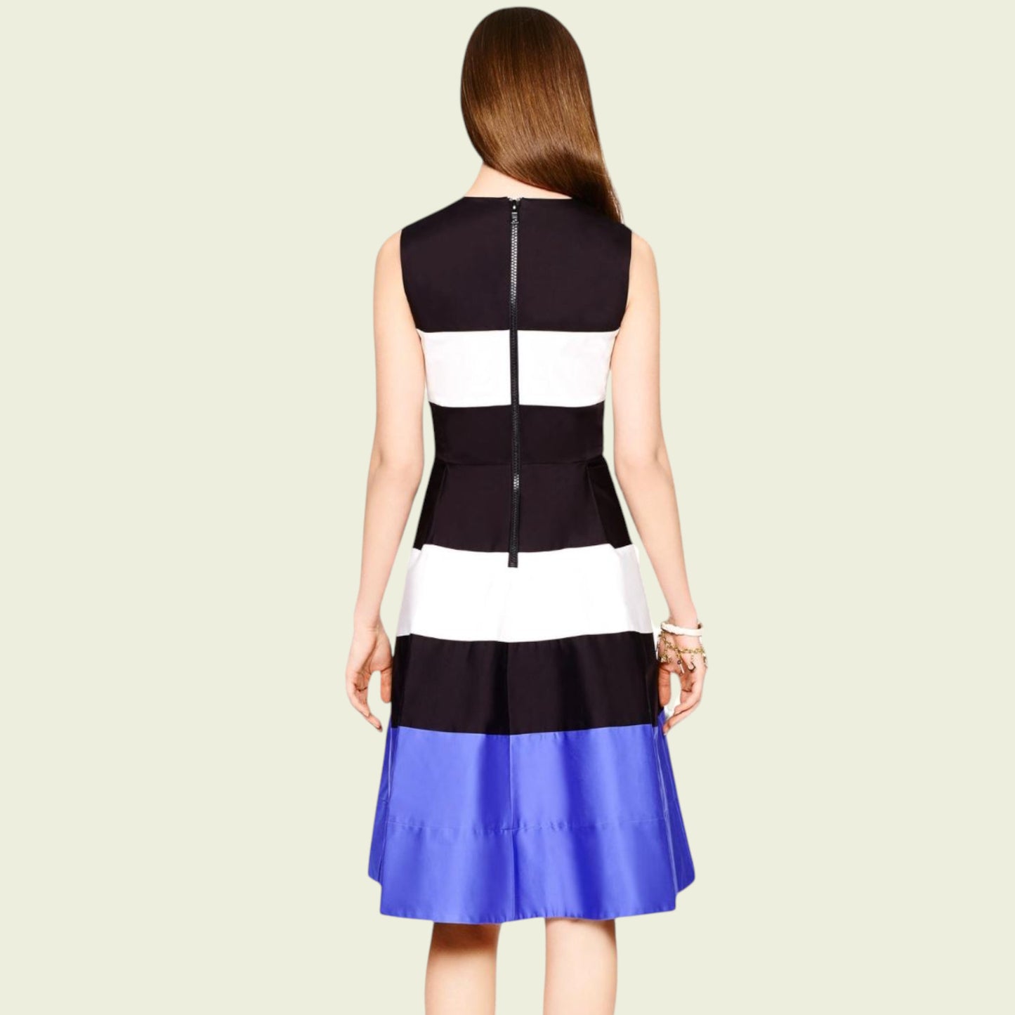 Woman wearing a black, white, and blue dress on a beige background