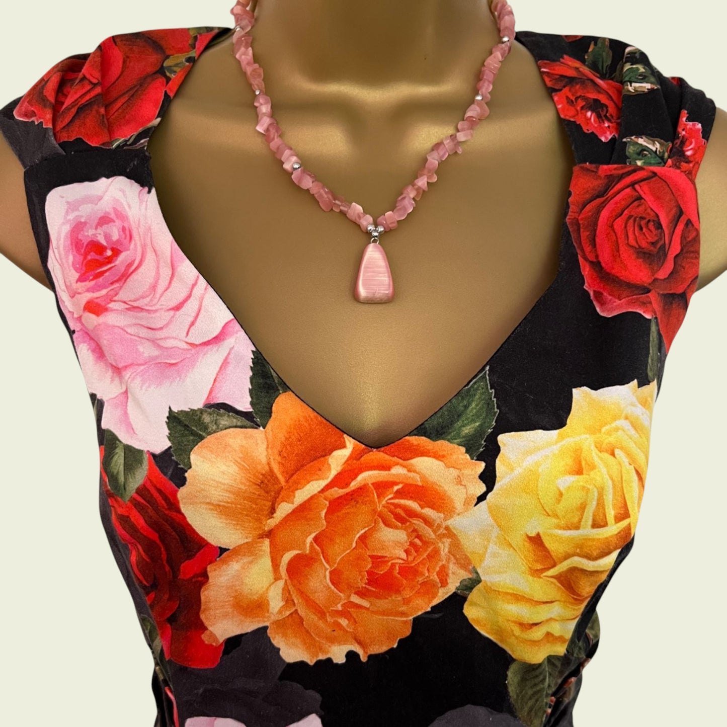Mannequin wearing a floral dress with a necklace on a plain background