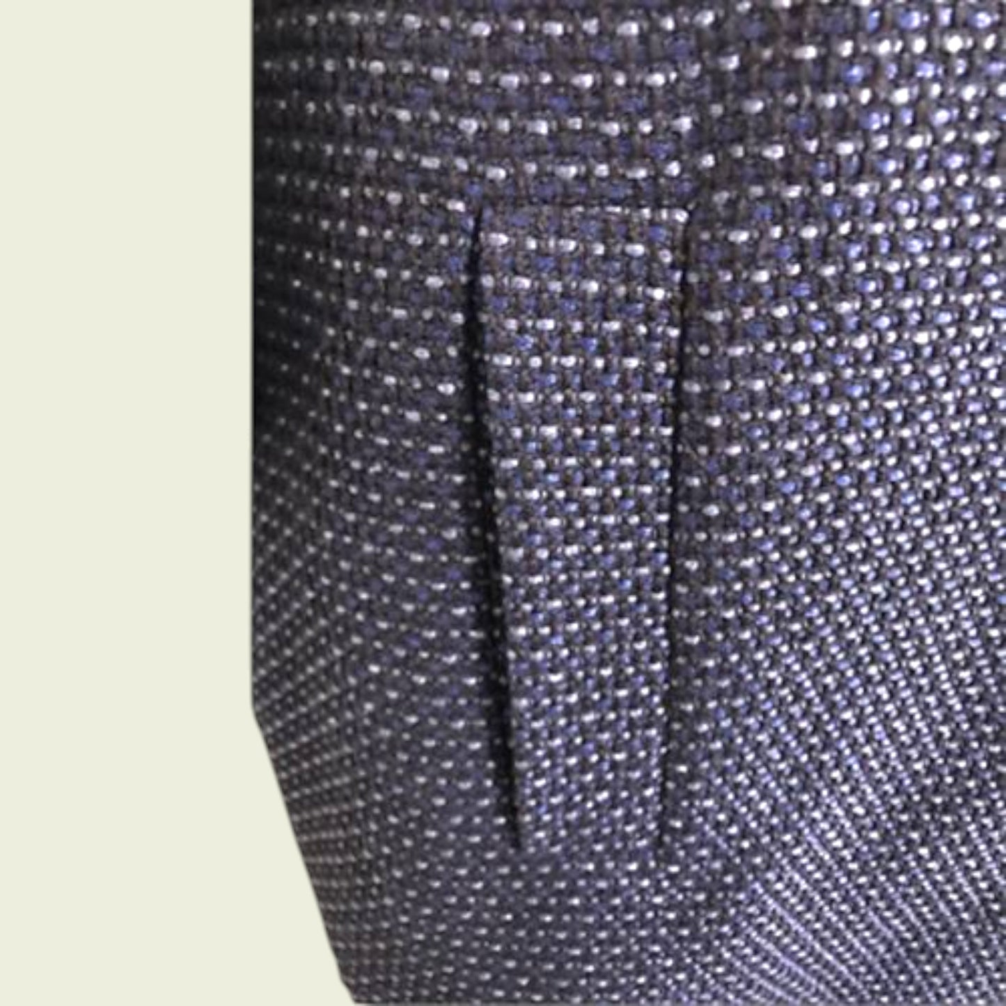 Close-up of a textured fabric with a pocket detail on a light beige background
