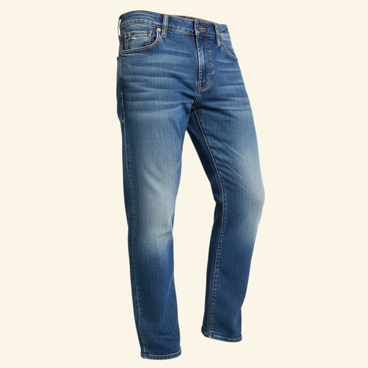 A pair of men's blue denim jeans with a faded wash, shown from a three-quarters angle against a solid cream background.
