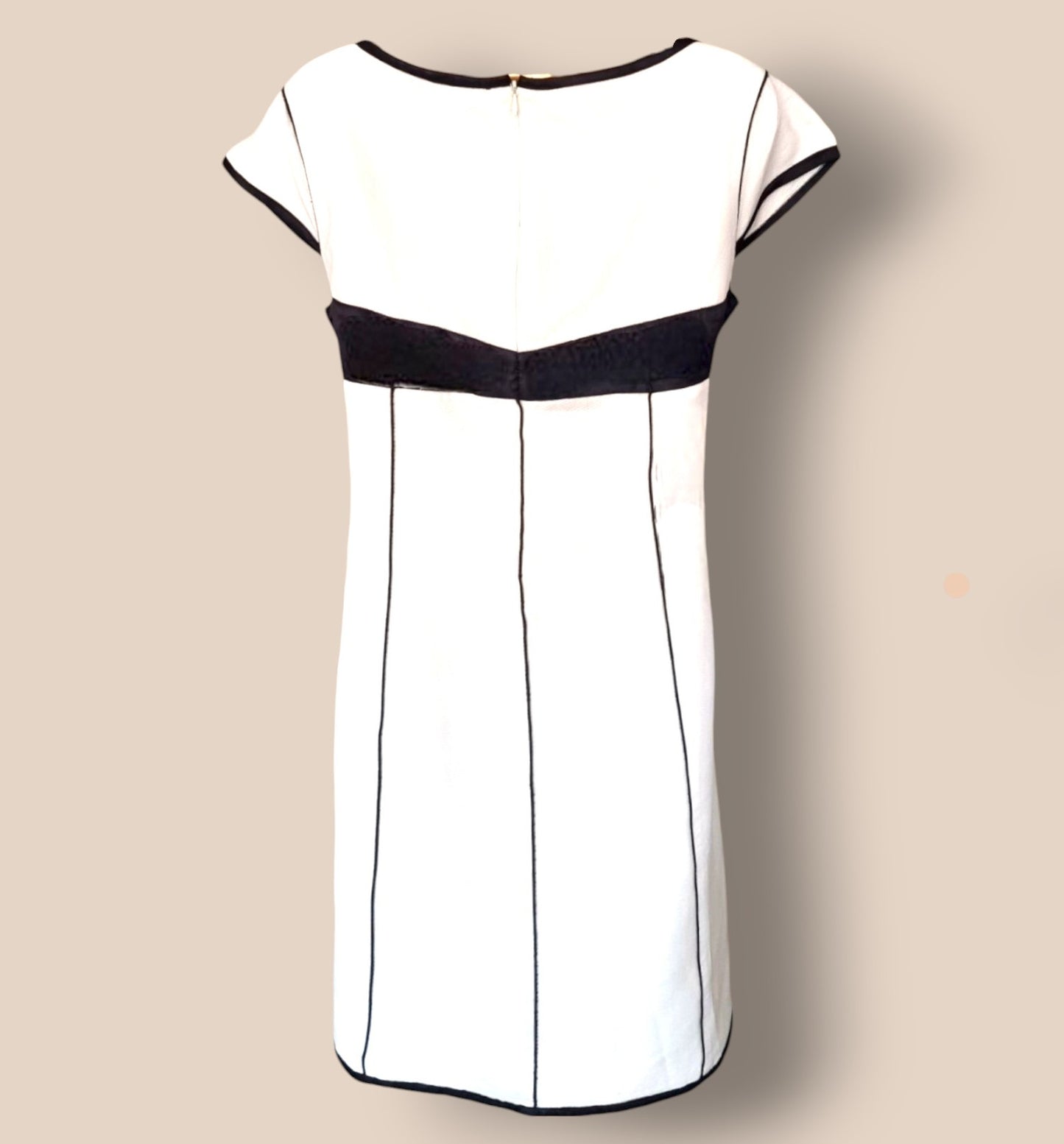 White dress with black accents on a beige background