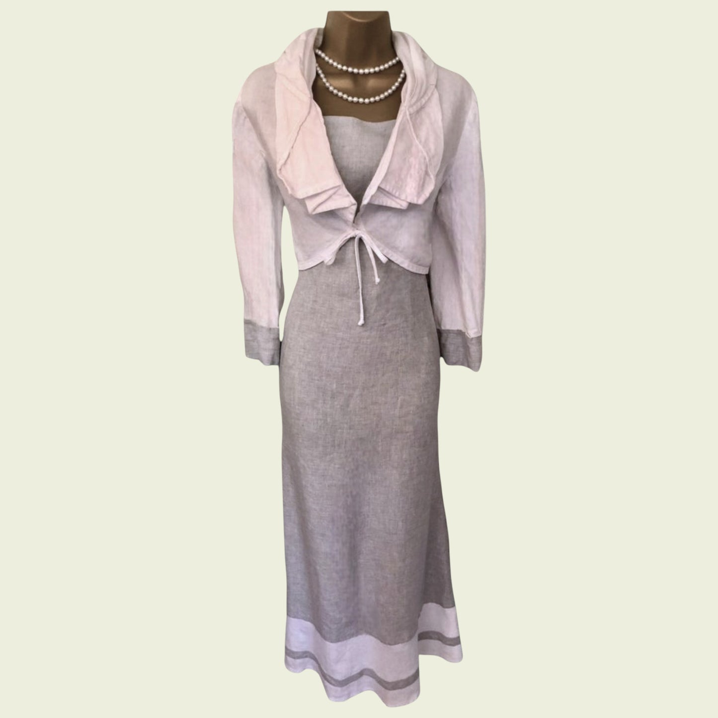 Gray dress with pink jacket on a mannequin against a light green background