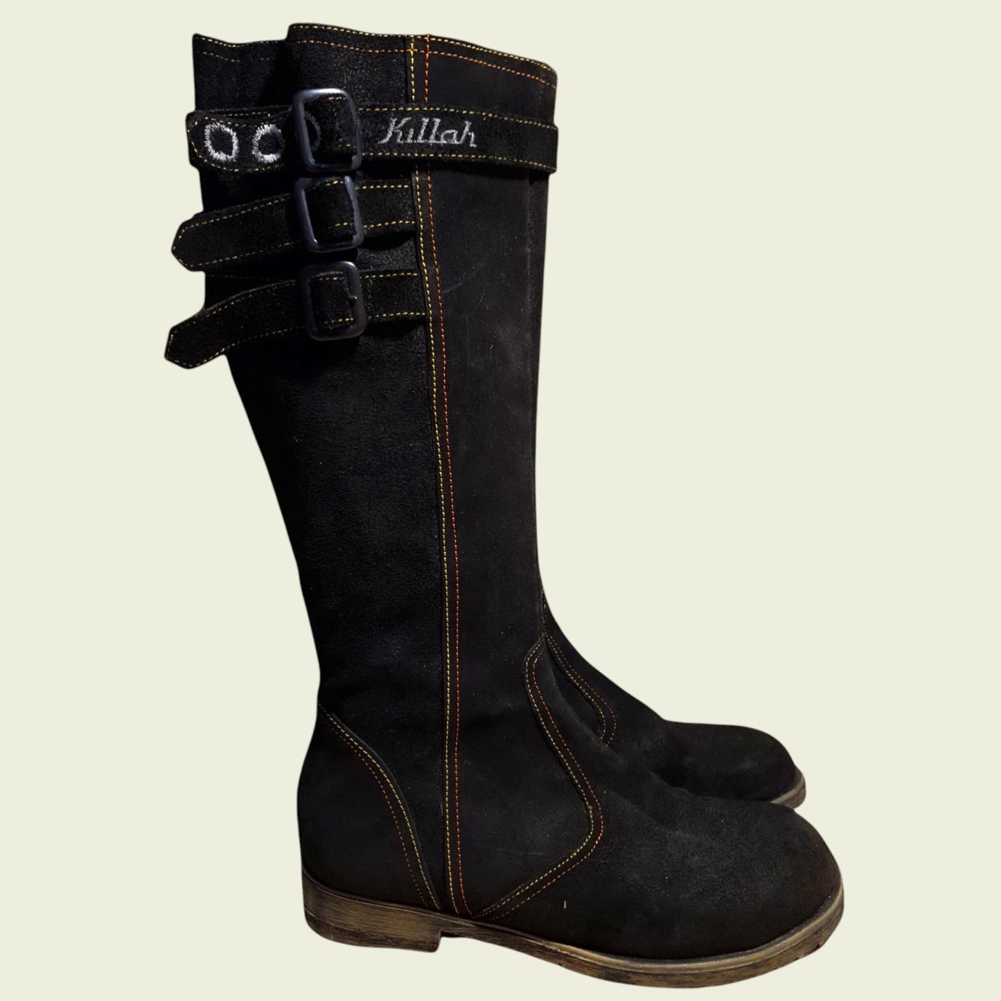 Black knee-high boots with buckles on a beige background