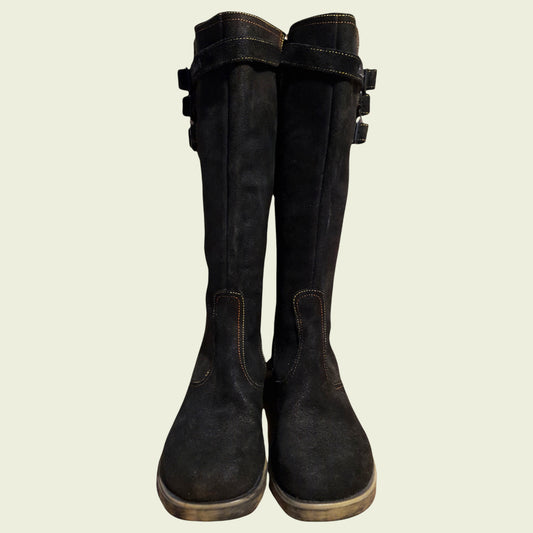 Pair of black boots with buckles on a beige background