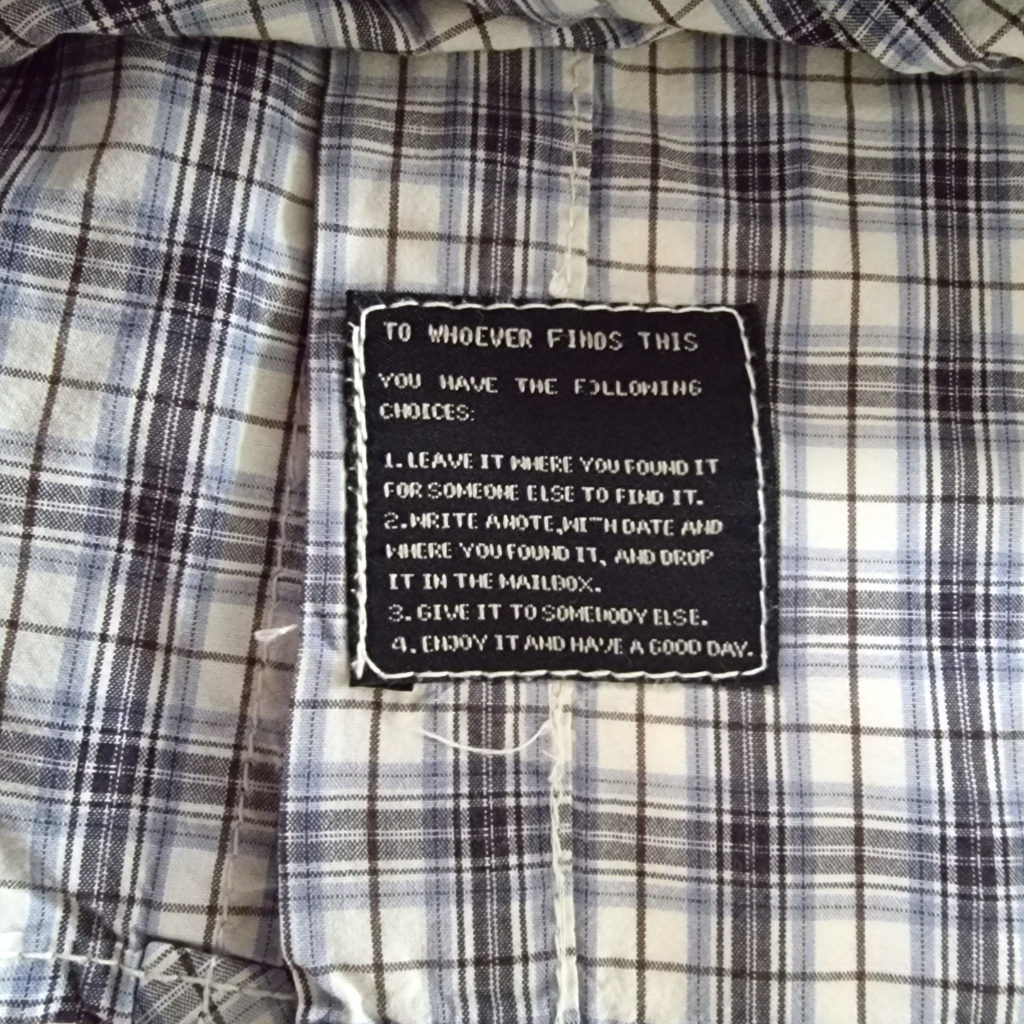 Plaid shirt with a black patch containing text on a checkered fabric background