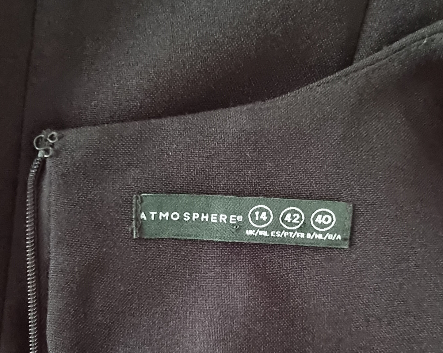 Close-up of a label on a dark fabric surface with 'Atmosphere' branding.