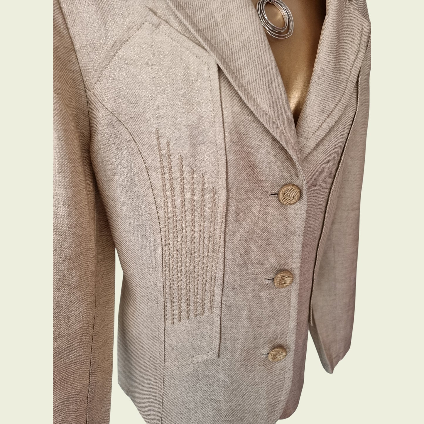Beige blazer with button details on a light beige background