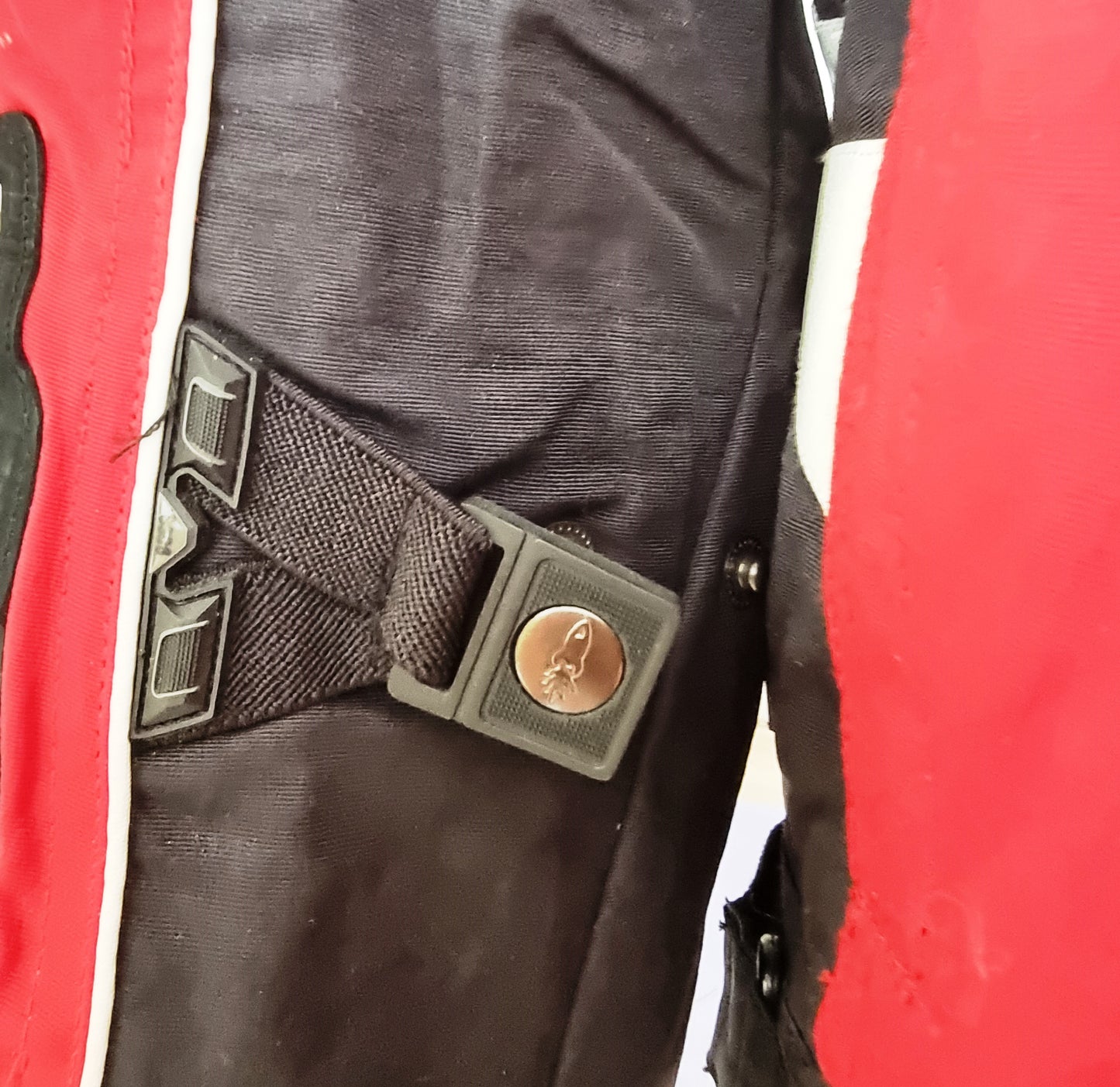 Close-up of a motor cycle jacket with a metal buckle on a red and black background