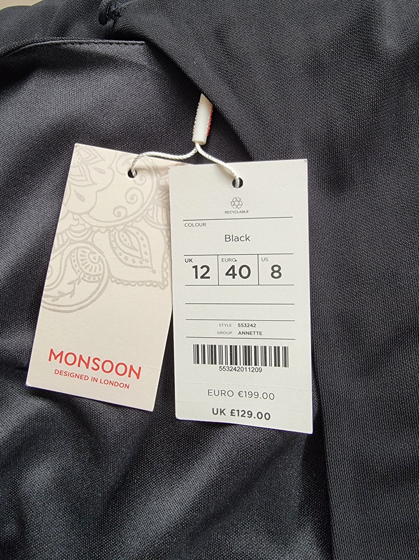 Clothing tag with size and brand information on a dark fabric background