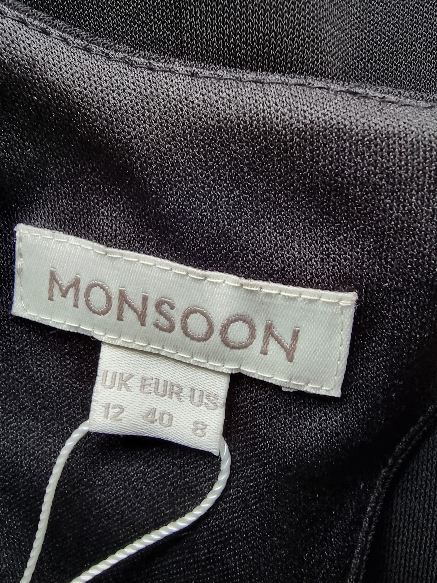 Close-up of a 'Monsoon' label on dark fabric