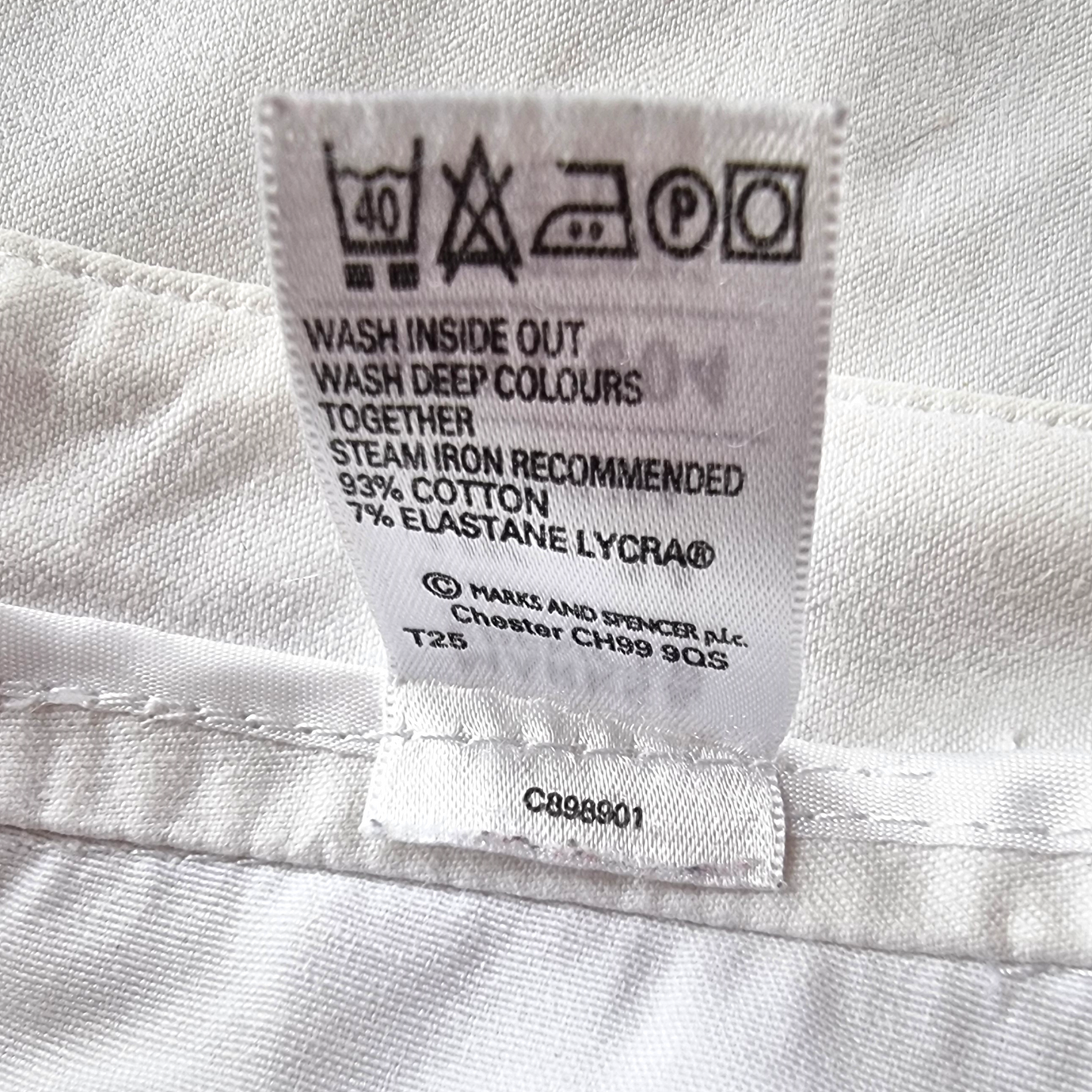 Fabric care label on a white garment with washing and ironing instructions.