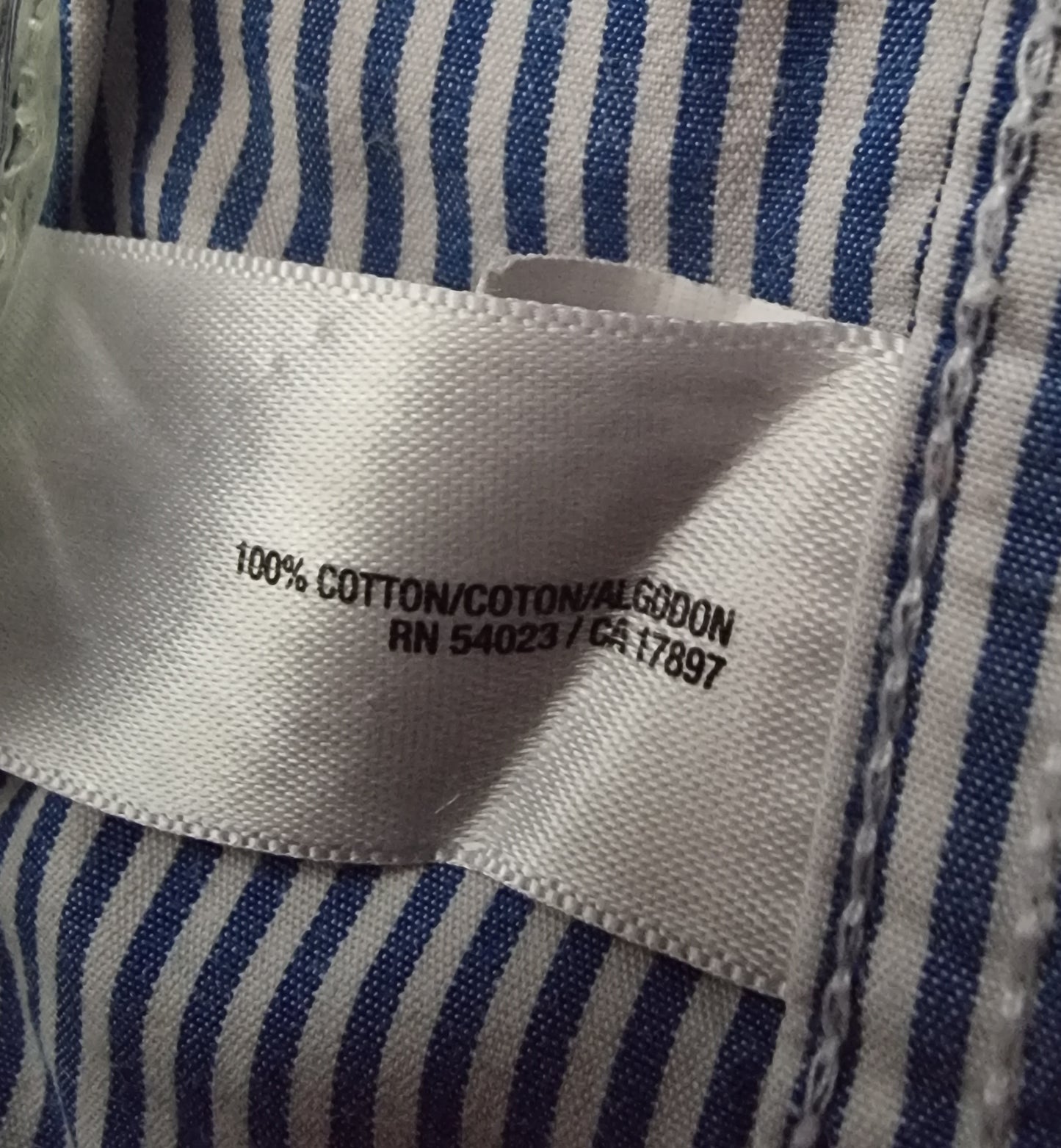 Close-up of a fabric label with text on a blue and white striped background