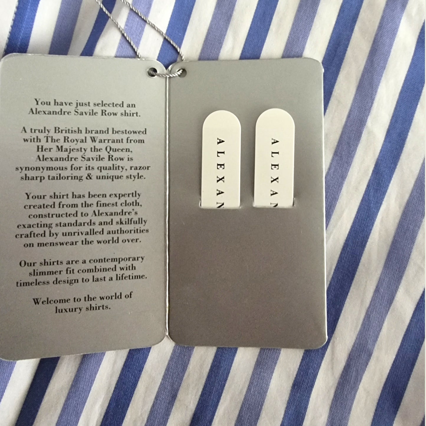 Alexandre Saville Row shirt tags on a striped fabric background