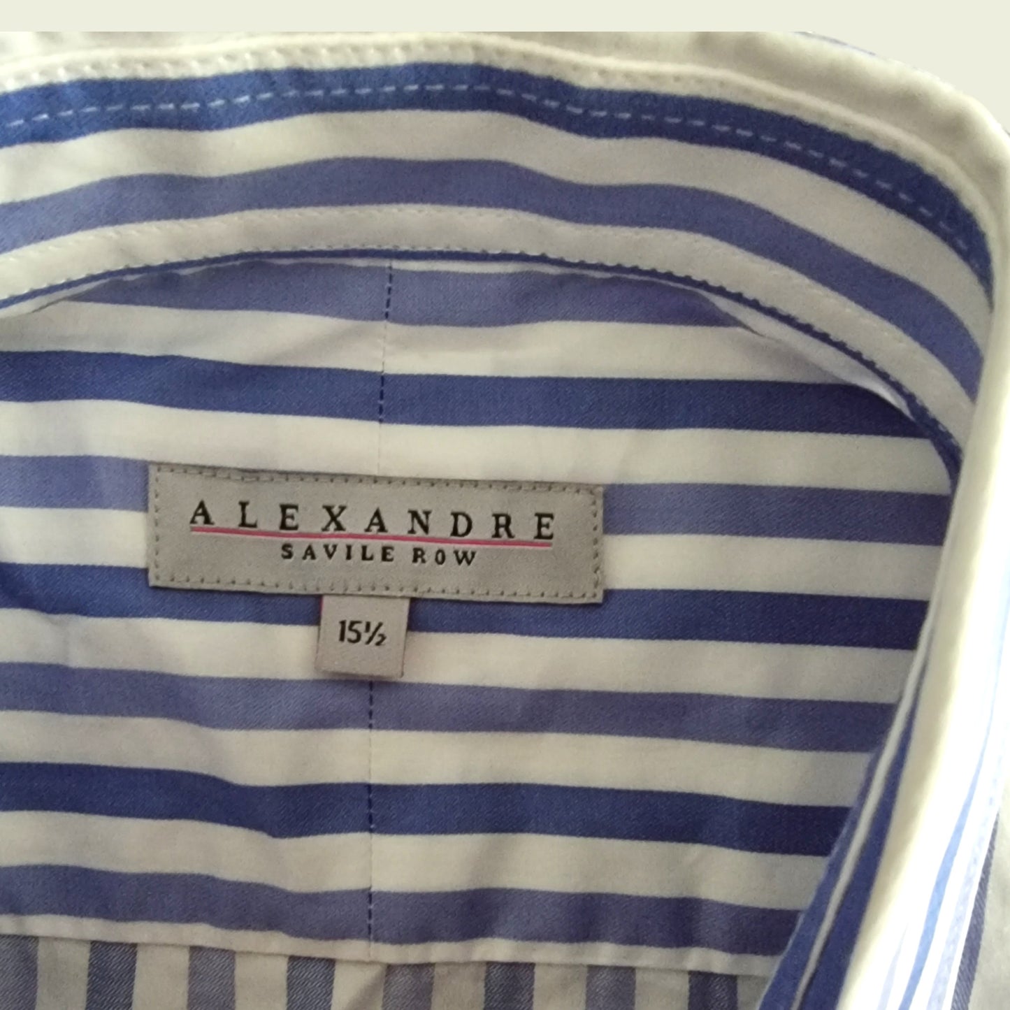 Close-up of a blue and white striped shirt with 'Alexandre Savile Row' label.