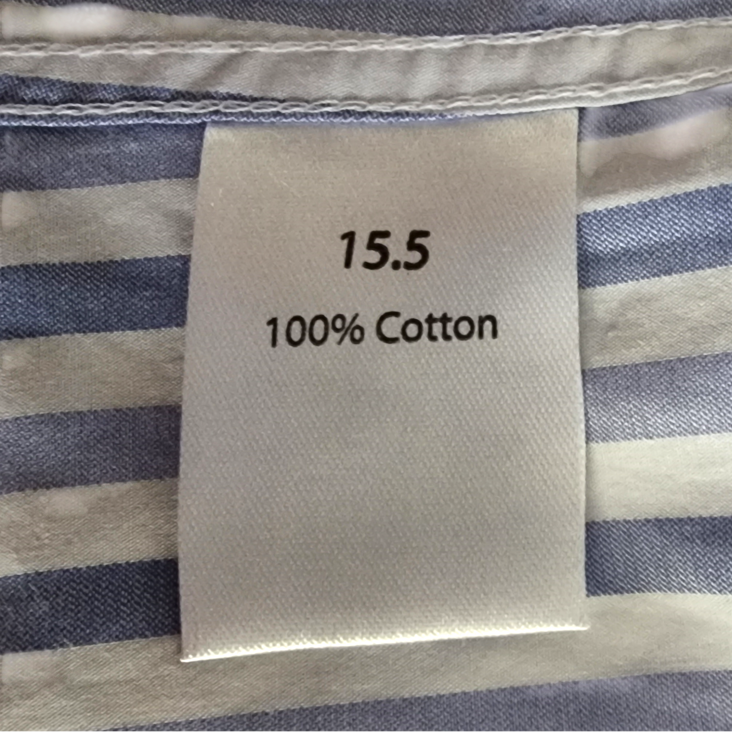 Label on striped fabric indicating size 15.5 and 100% cotton