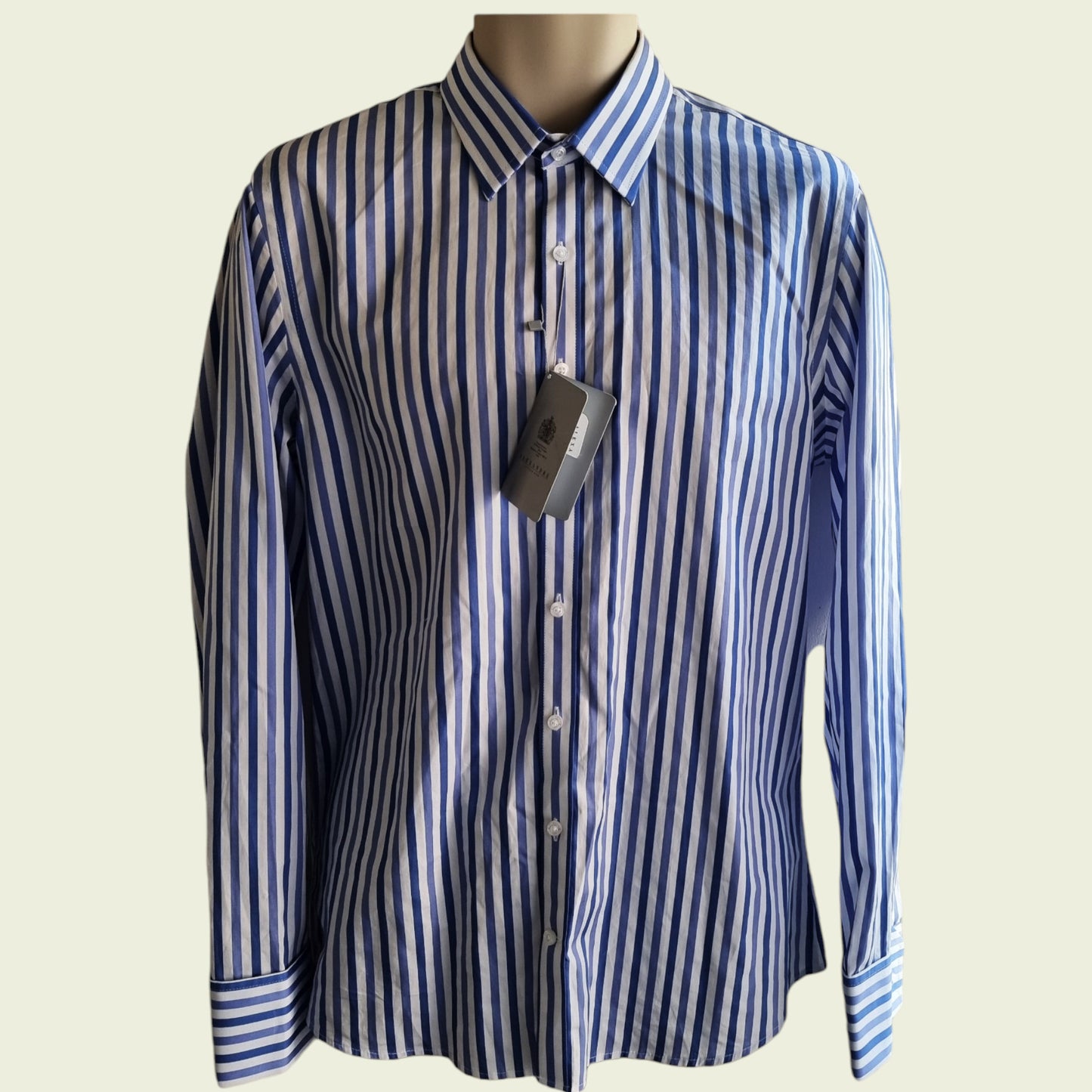 Blue and white striped shirt on a mannequin with a visible tag against a beige background