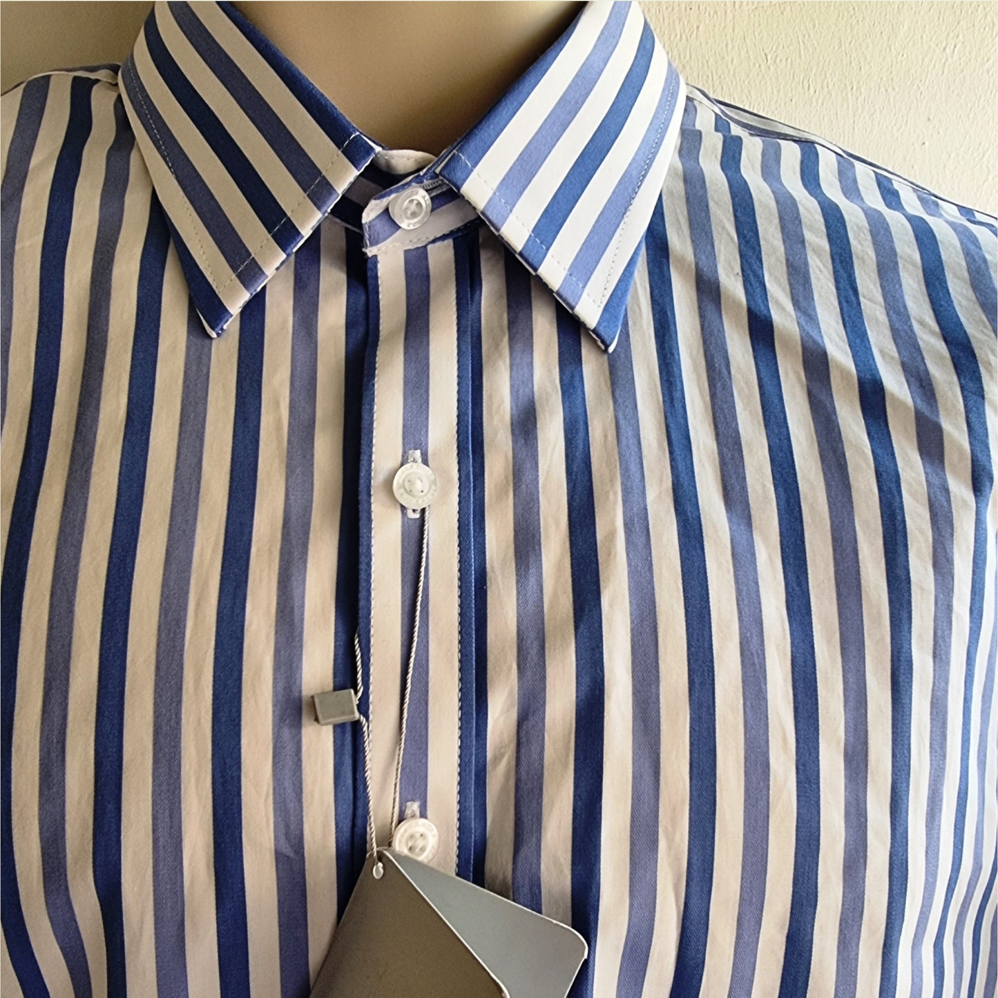 Close-up of a blue and white striped shirt on a mannequin with a beige background