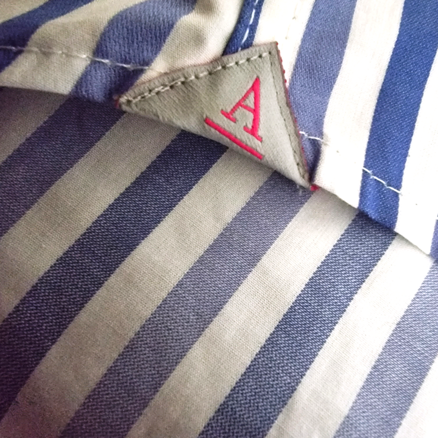 Close-up of a striped fabric with a brand label featuring a red 'A'.