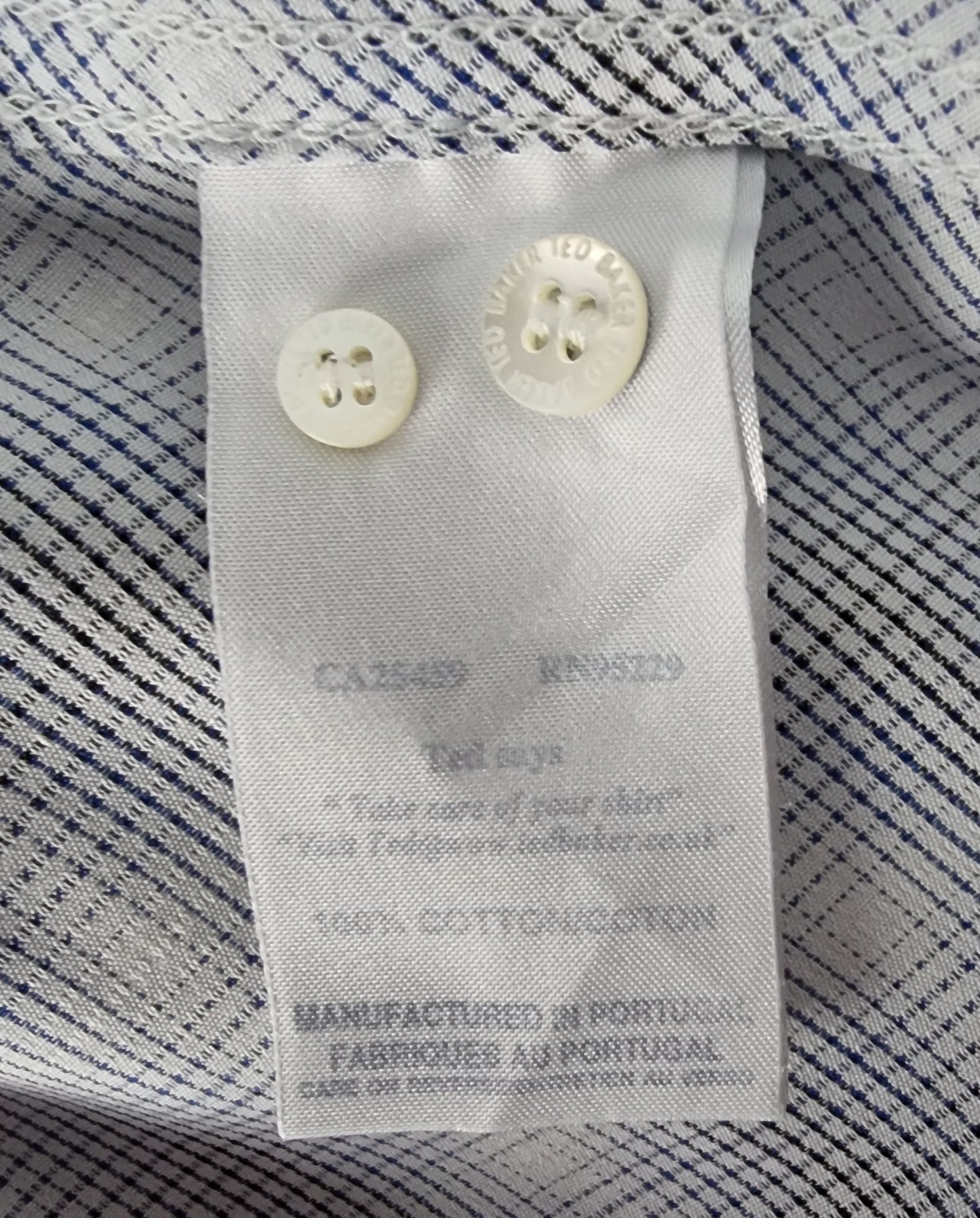 Close-up of a label on a striped shirt with visible text and buttons.