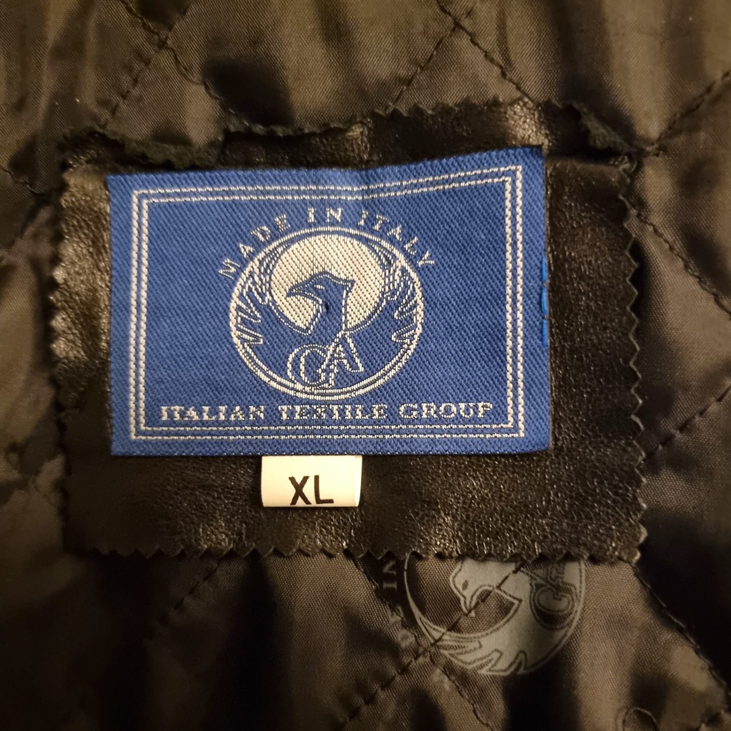 Textile label on a dark fabric background with 'Made in Italy' and 'Italian Textile Group' branding.
