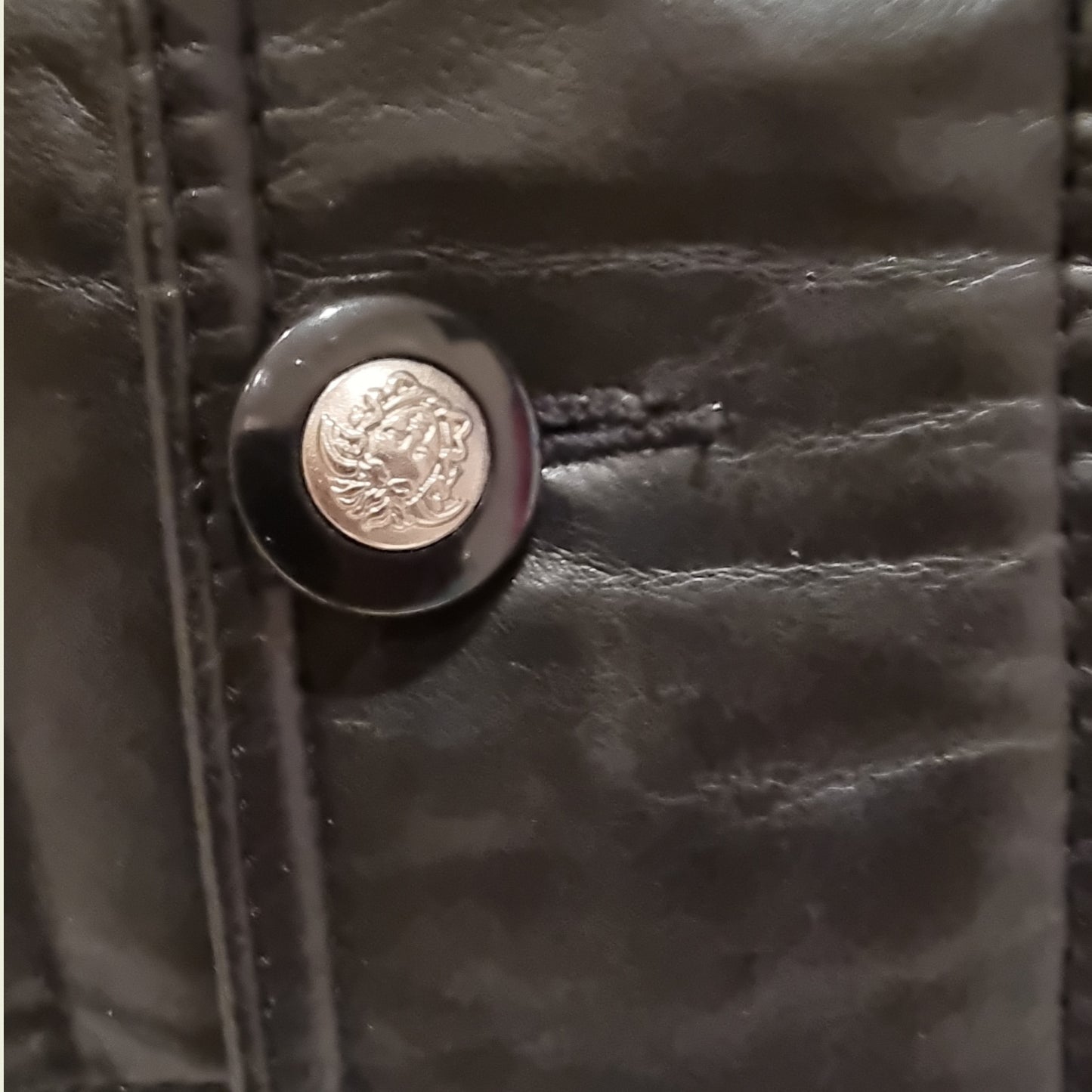 Close-up of a black leather button with a metallic emblem on a dark background
