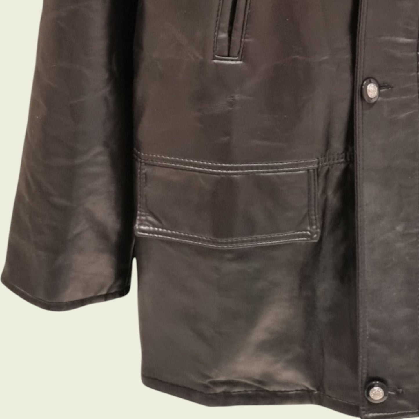 Close-up of a Black leather jacket with a pocket and buttons on a beige background