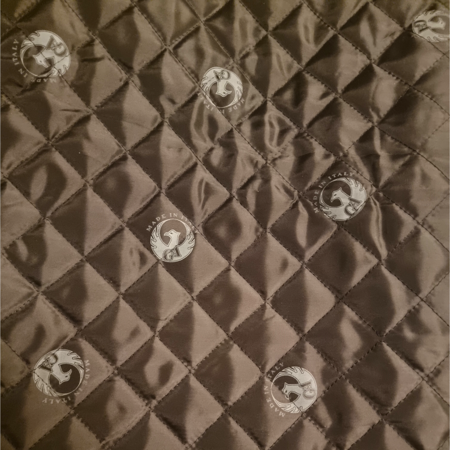 Quilted fabric with diamond pattern and button-like embellishments on a brown background