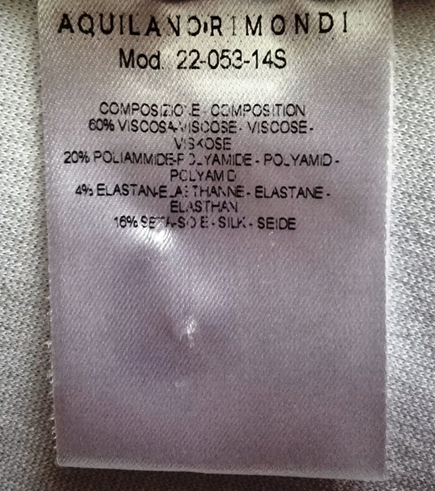 Fabric label with Aquilano Rimondi branding and material composition details on a textured fabric background.