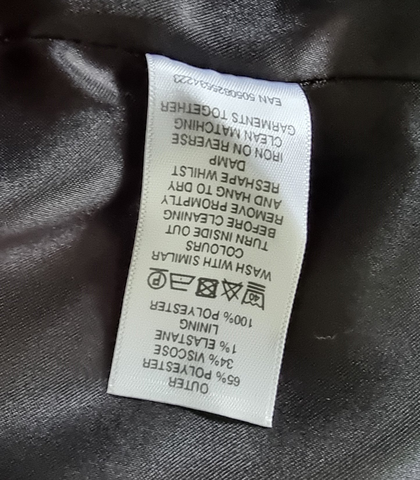 Clothing label with fabric composition and care instructions on a dark fabric background