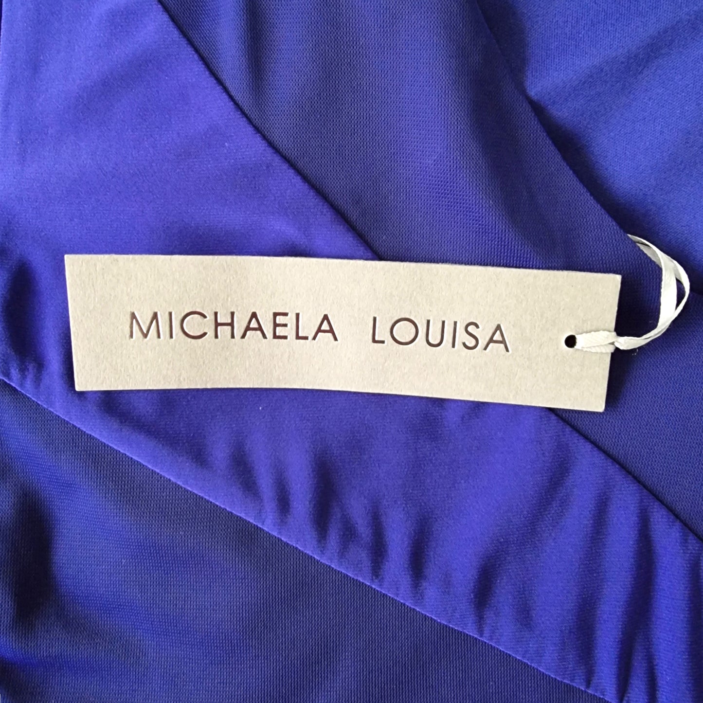 Name tag with 'MICHAELA LOUISA' on a blue fabric background
