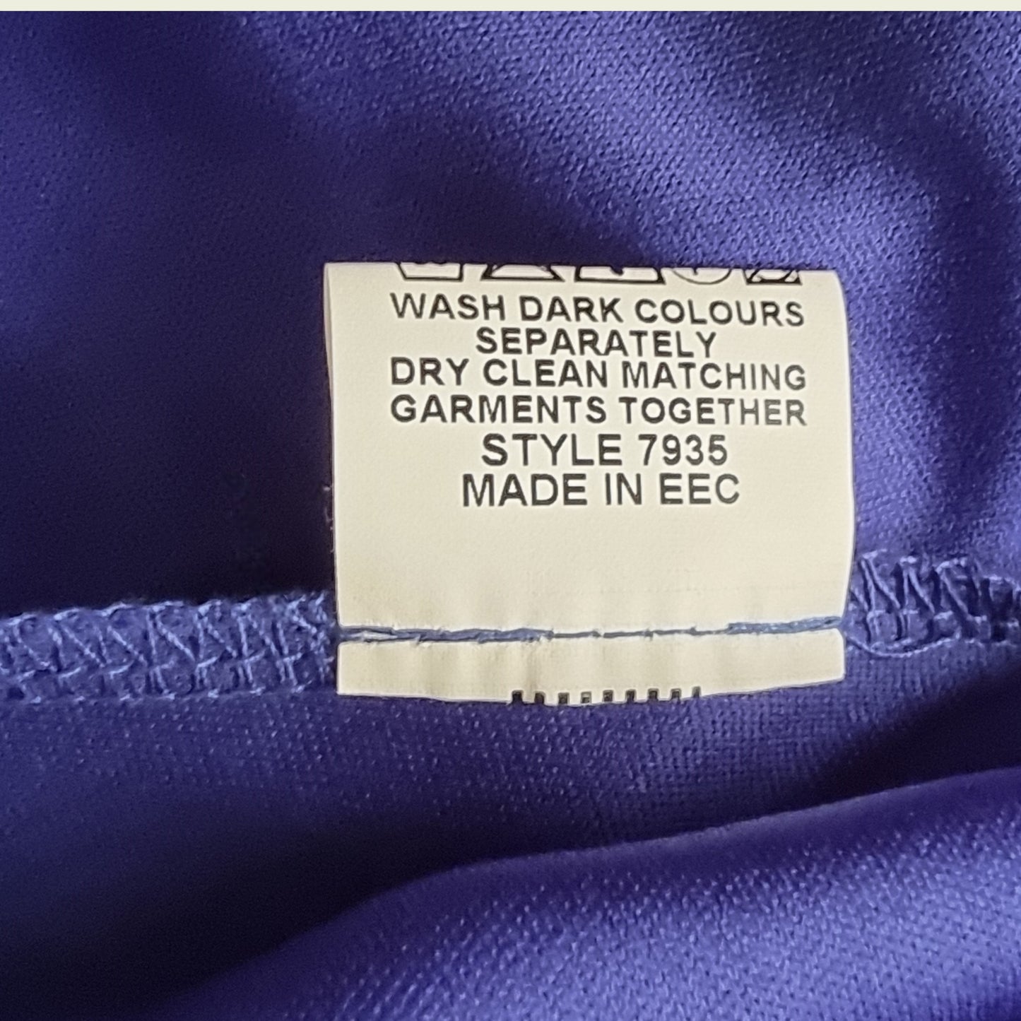 Clothing label on a blue fabric background with text instructions.
