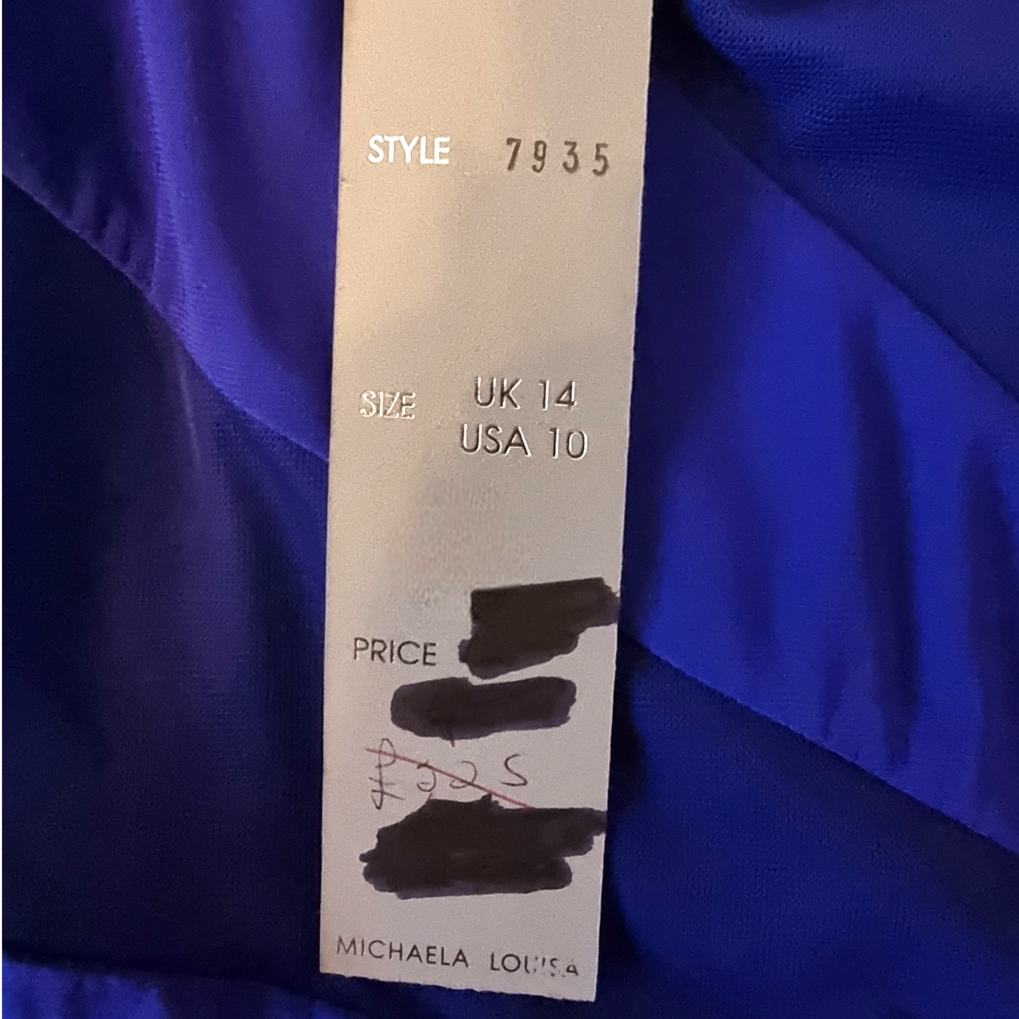 Clothing tag with size, style, and price information on a blue fabric background