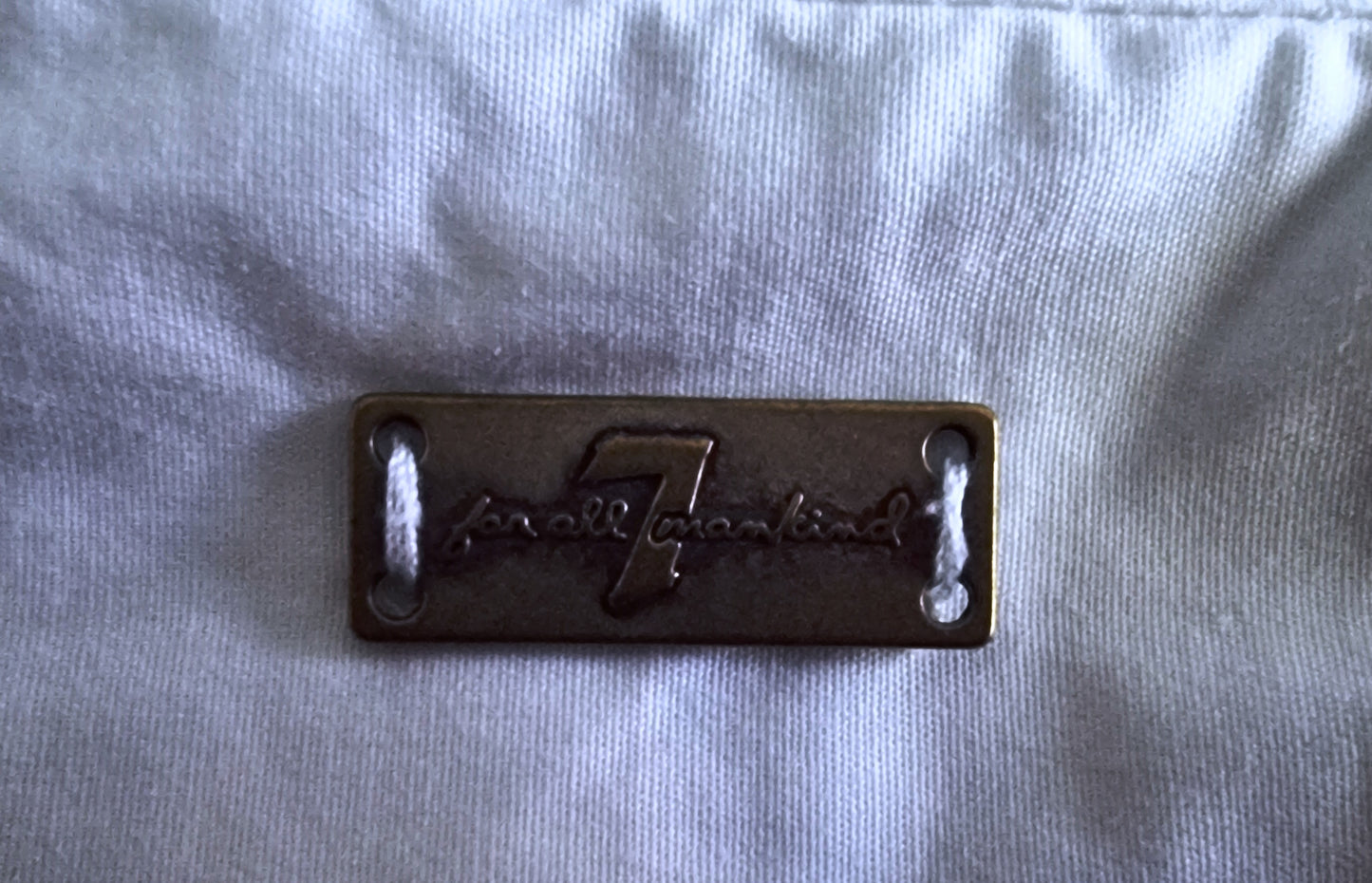 Metallic badge with 'Fender' logo on a light gray fabric background
