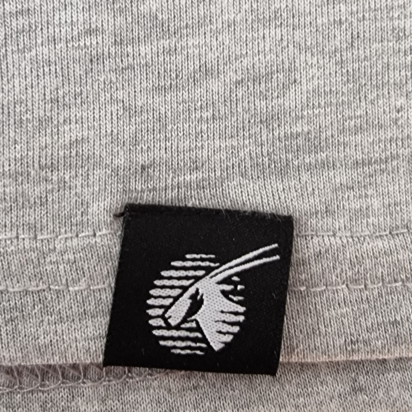 Black label with white logo on a gray fabric background