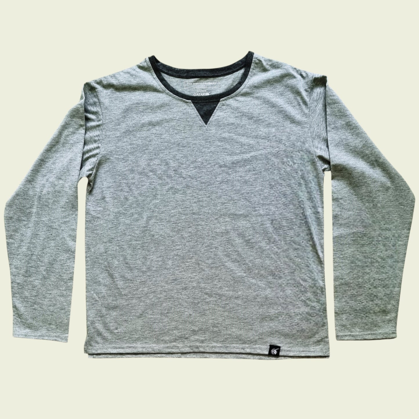 Gray long-sleeve shirt with black trim on a beige background