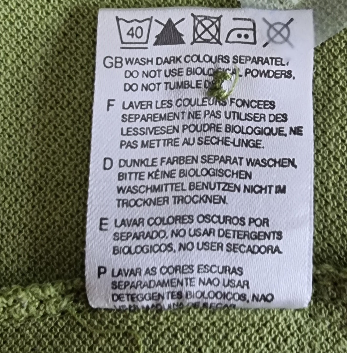 Washing instructions label on a green fabric background