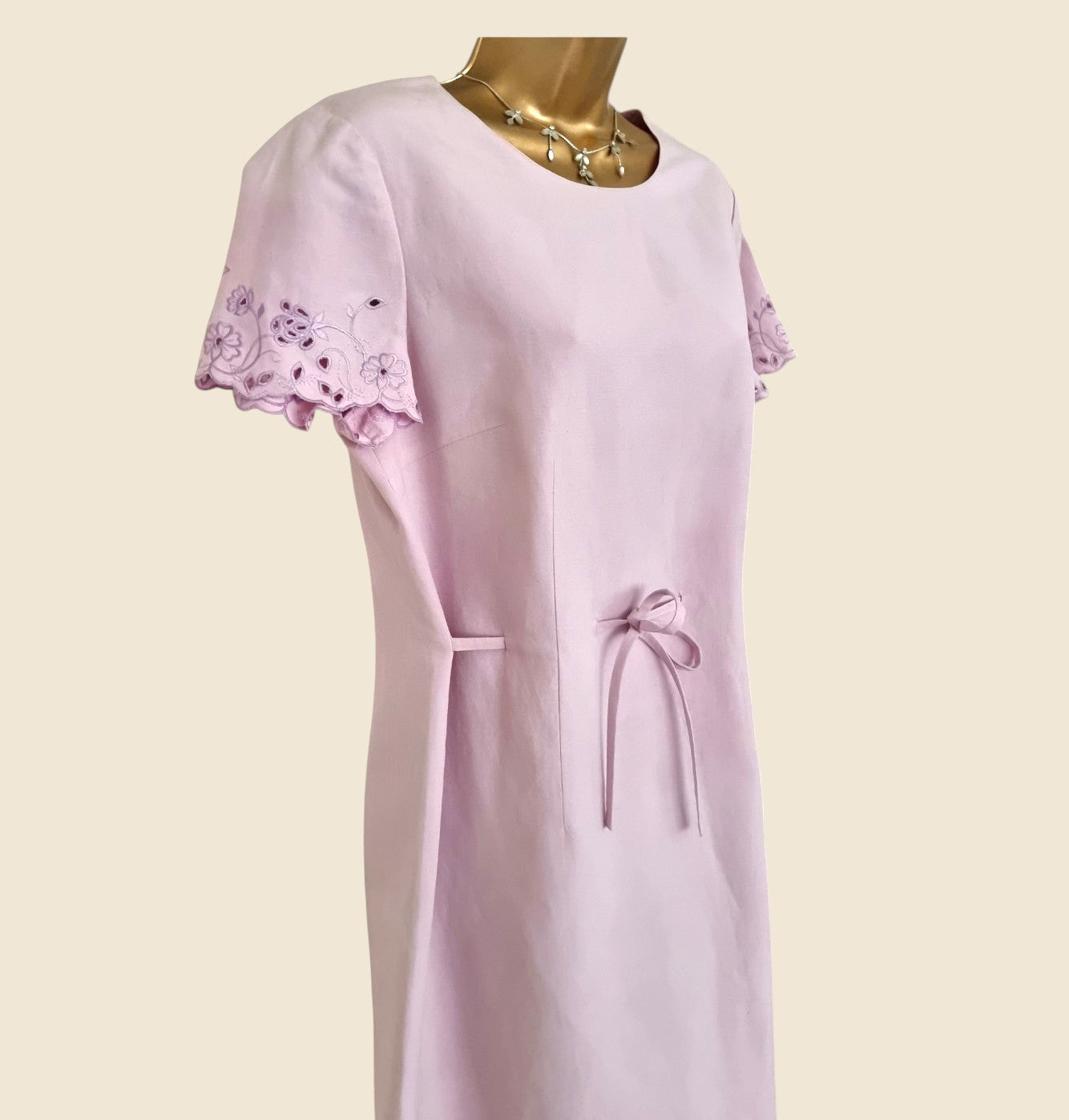 Light purple dress with lace sleeves on a mannequin against a beige background