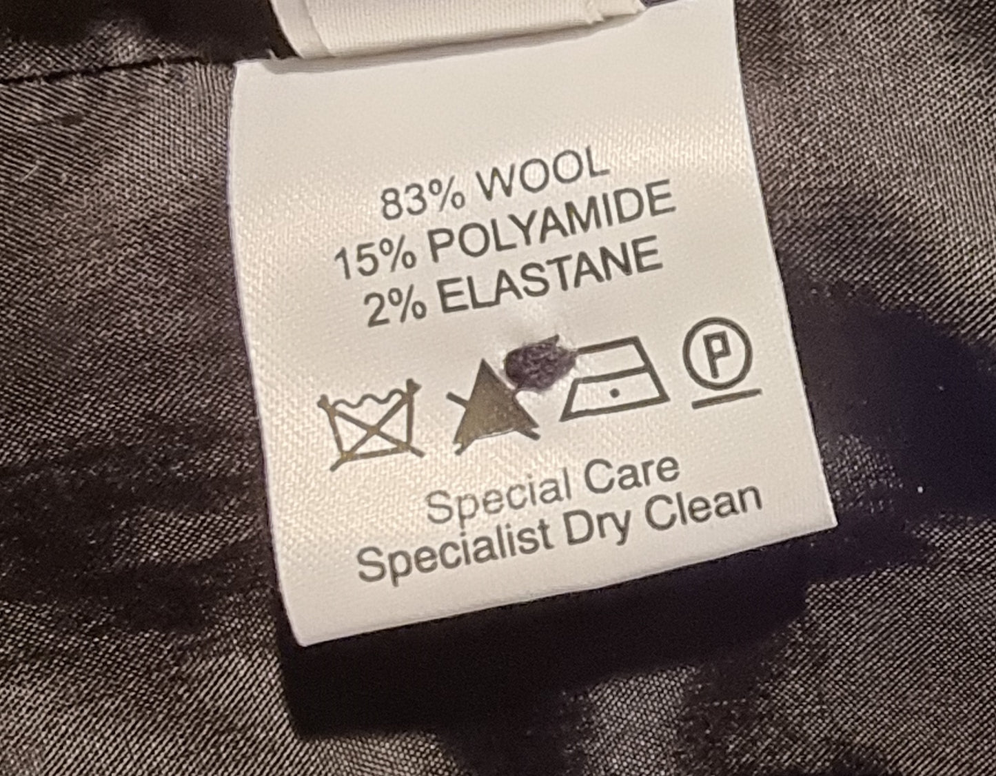 Clothing label with fabric composition and care instructions on a dark fabric background