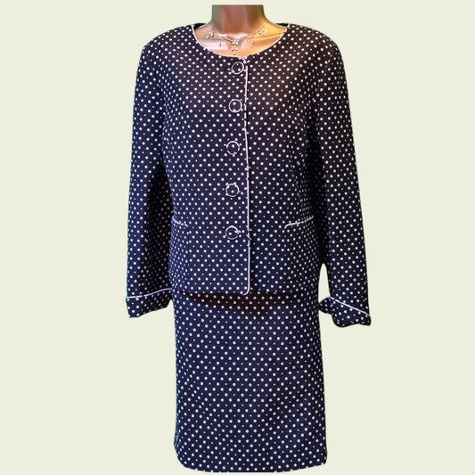 Black polka dot dress with a matching jacket on a light beige background